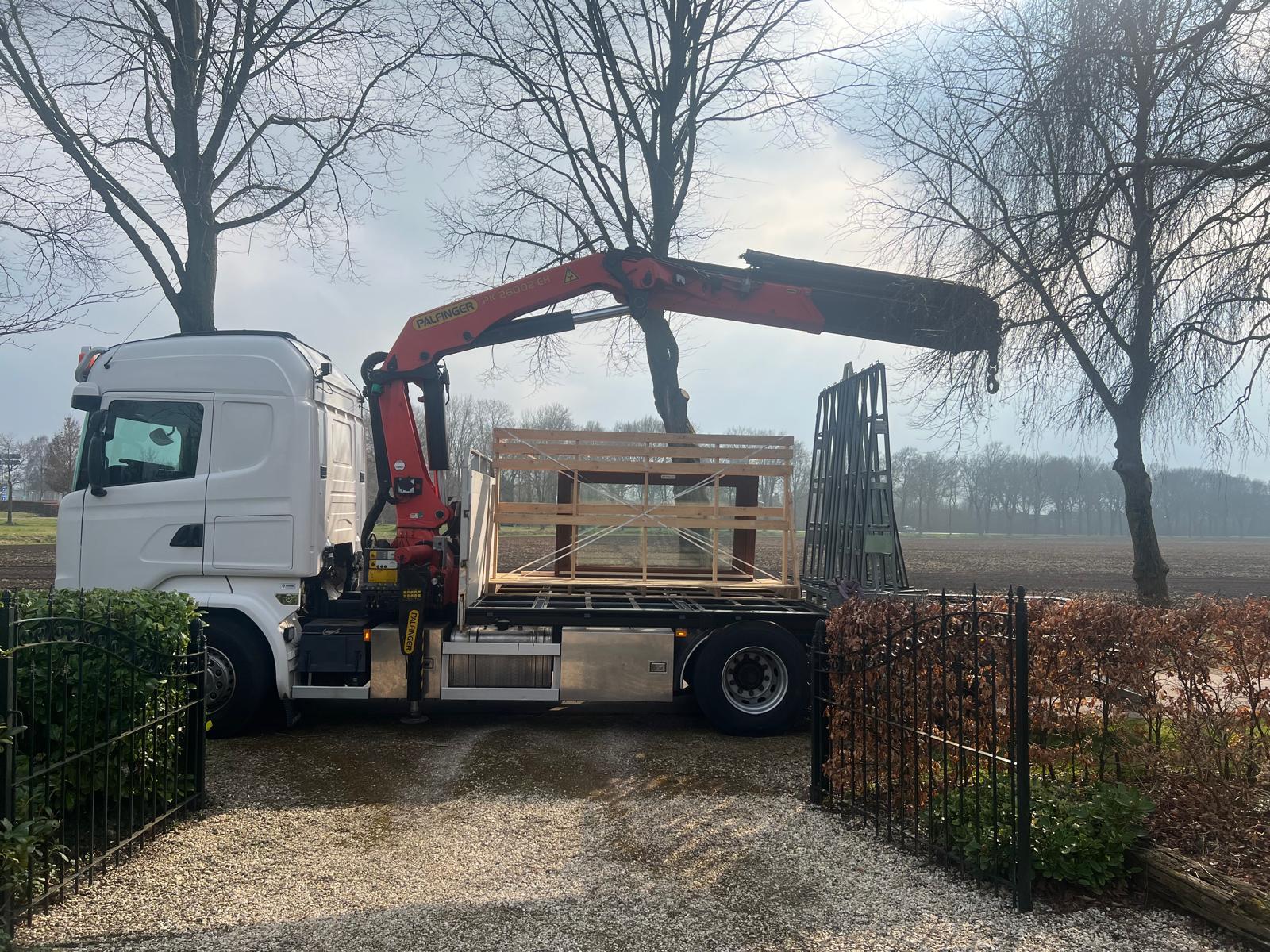 Vrachtwagen met laadkraan beladen met houtconstructie